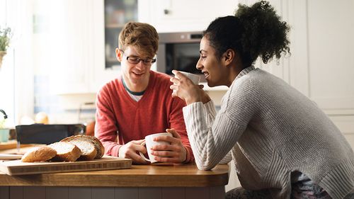 Young couple discussing insurance while drinking coffee in their kitchen.